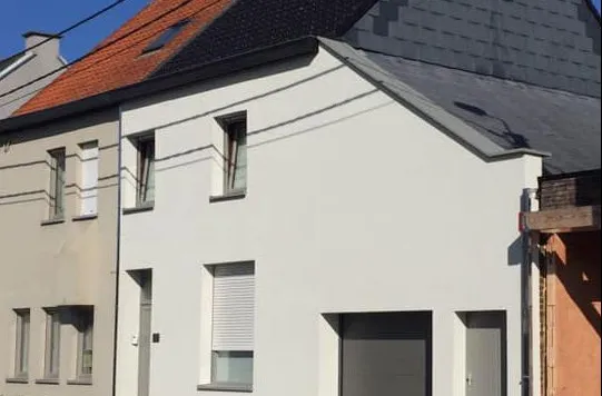 Voorgevel van twee aaneengeschakelde woningen met witte en lichtbeige crepi-afwerking en hellende daken met donkere pannen.